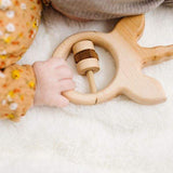 small infant hand holding onto unicorn wooden baby rattle.