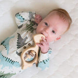 baby boy chewing on organic wooden baby dinosaur rattle.